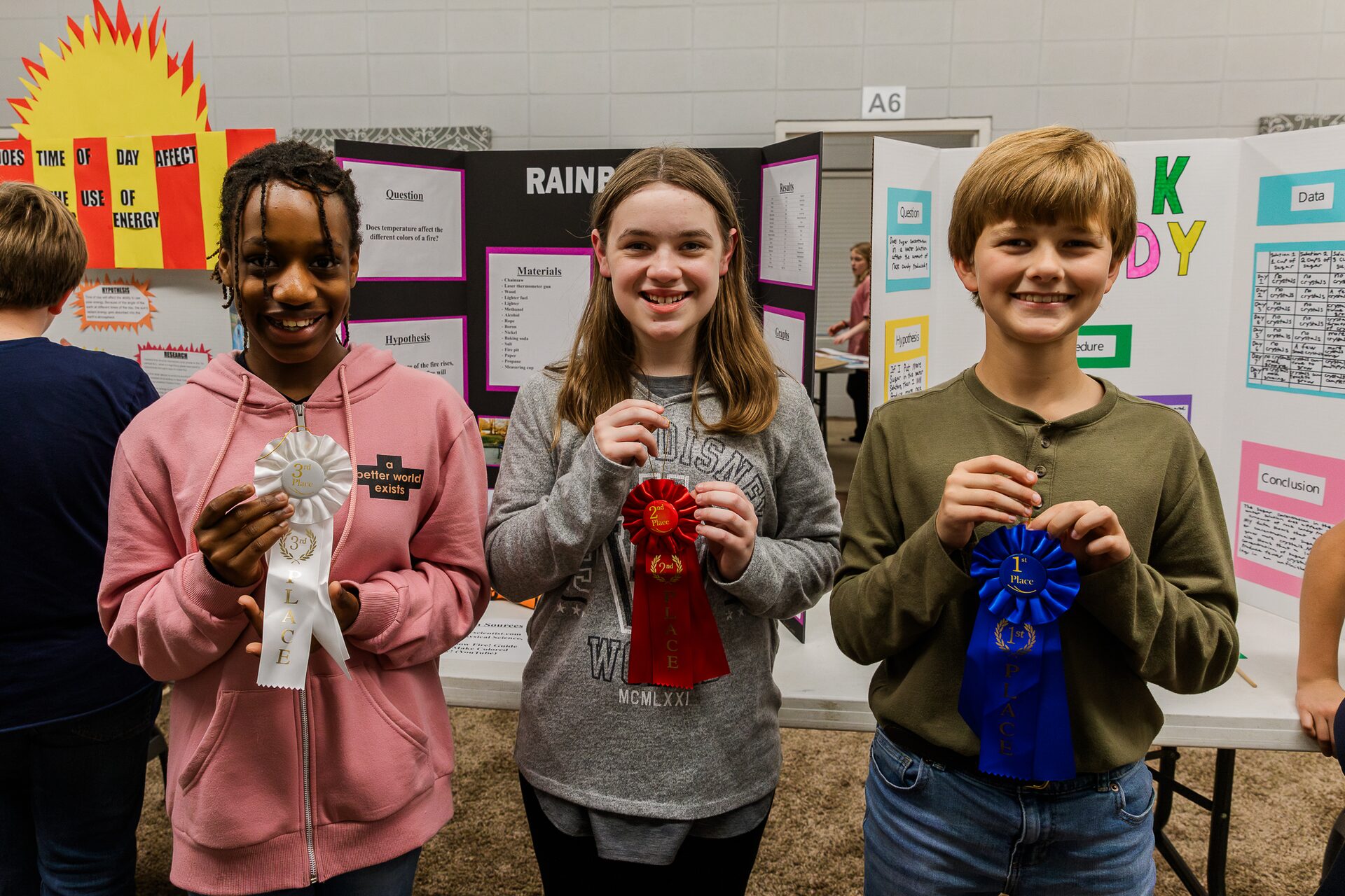 Students at a science fair, holding their award ribbons